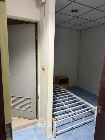 Compact bedroom with metal bed frame and blue tiled floor, ideal for minimalist living.