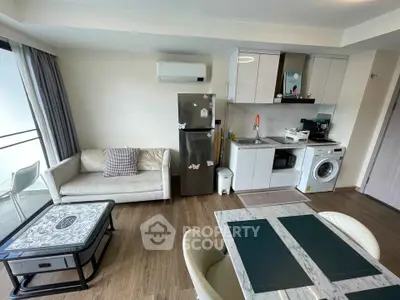 Modern open-layout living room with kitchen, featuring stylish furniture and appliances, ideal for urban living.