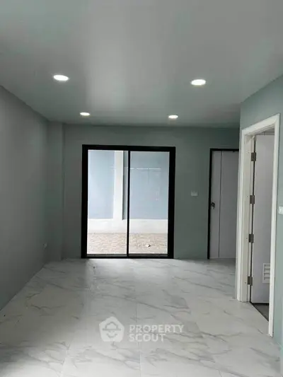 Modern interior with marble flooring and sliding glass doors leading to outdoor space.