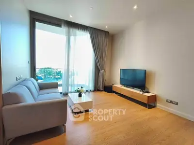 Modern living room with sleek furniture and large window offering natural light and balcony access.