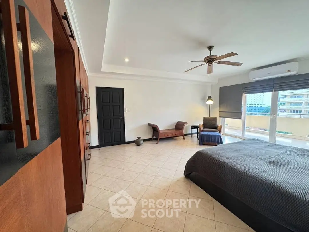 Spacious bedroom with modern decor and large windows offering city views.