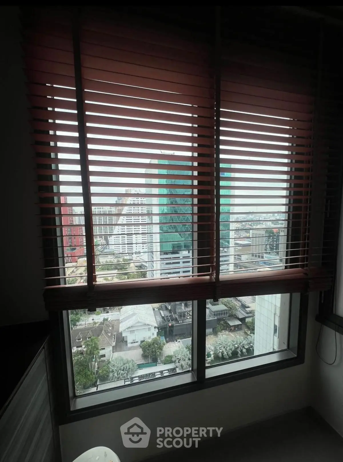 Stunning city view from high-rise apartment window with modern blinds.
