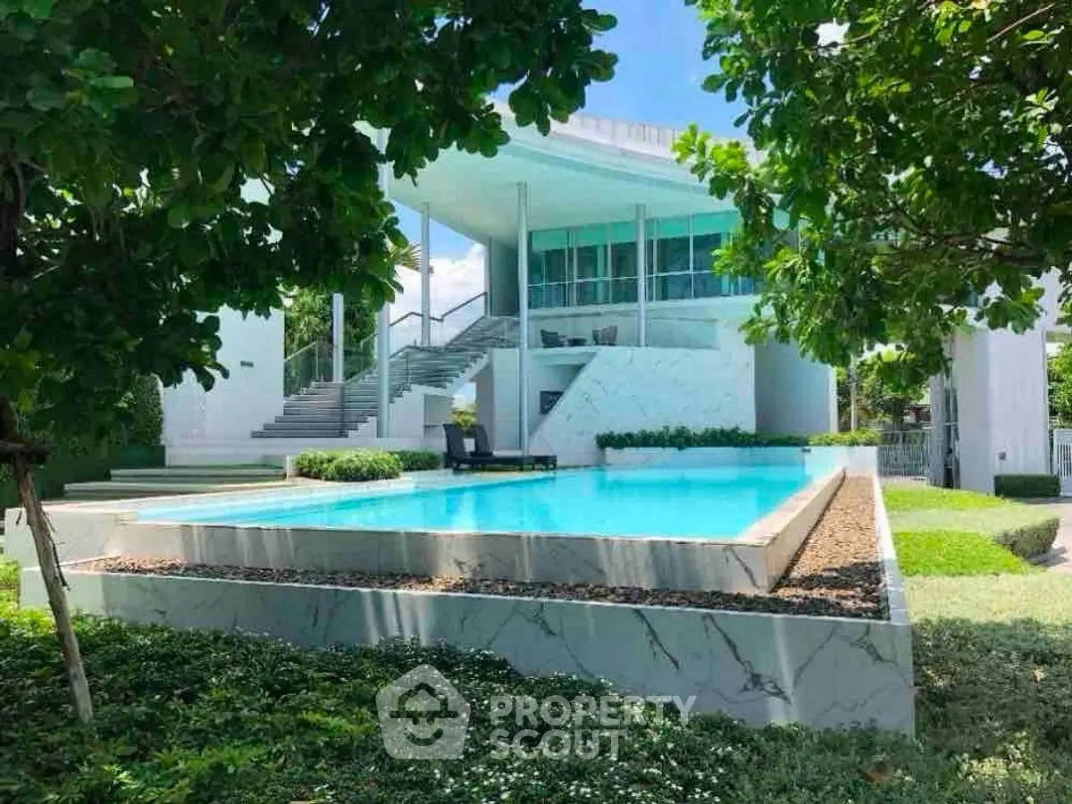 Luxurious modern home with stunning pool and lush greenery, perfect for serene living.