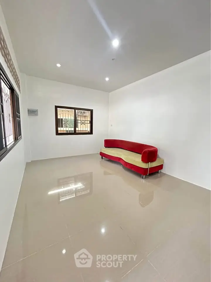 Spacious living room with modern red sofa and large windows, perfect for natural light.