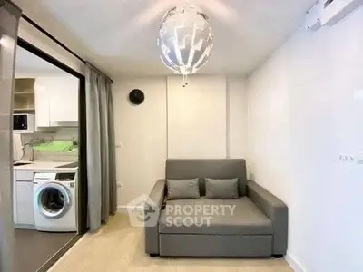Modern compact living room with sofa and washing machine in open layout.