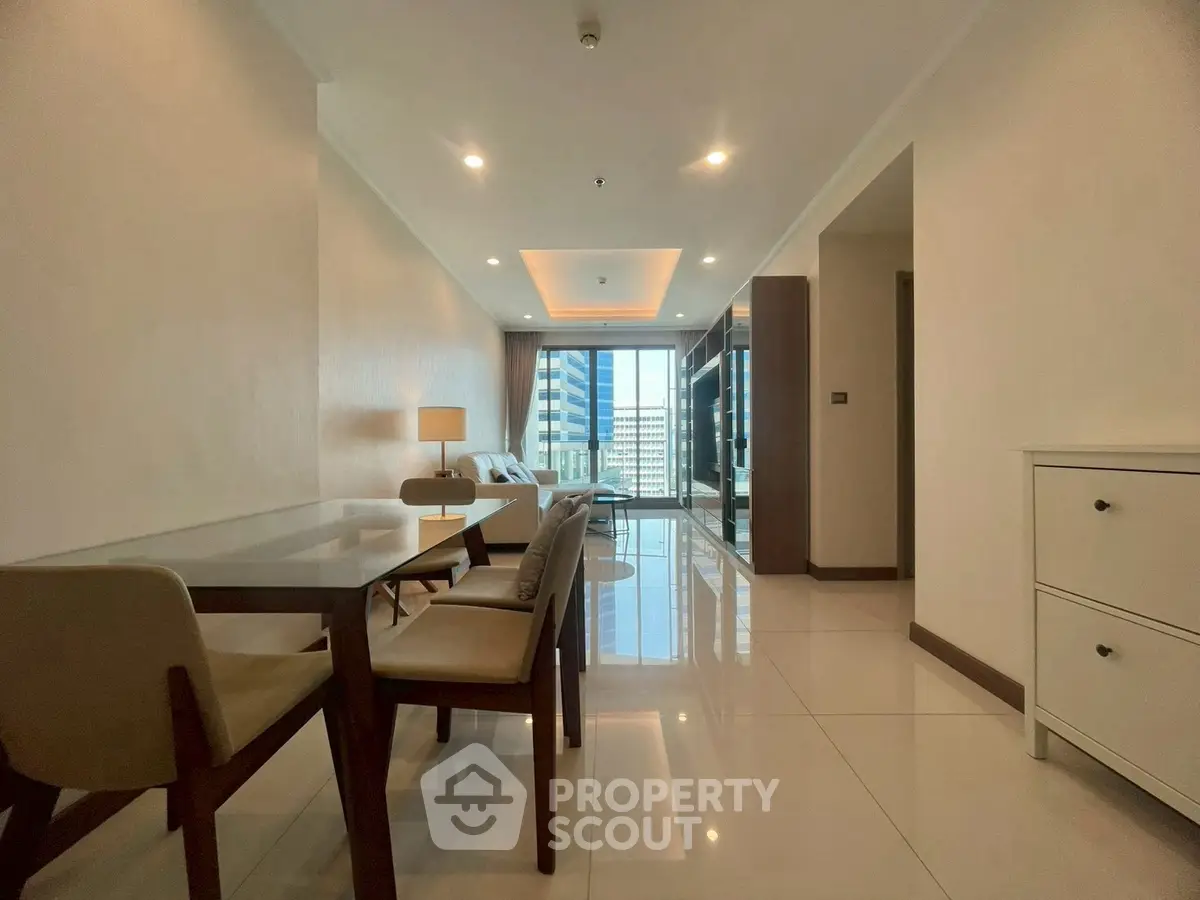 Spacious modern living room with dining area and city view, featuring sleek furniture and bright lighting.