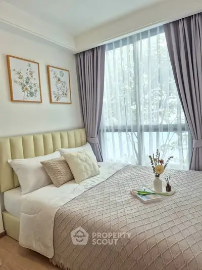 Cozy bedroom with elegant decor and large window offering natural light.