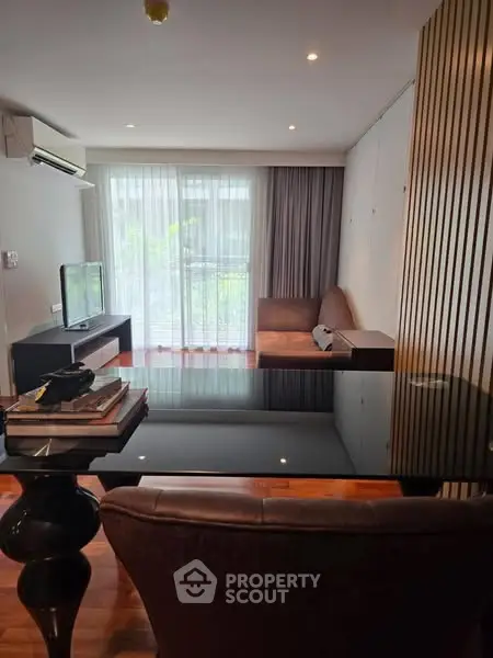 Modern living room with sleek furniture and large window offering natural light.