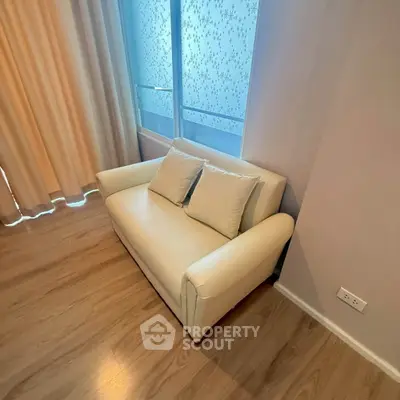 Cozy living room corner with elegant white sofa and large window view.