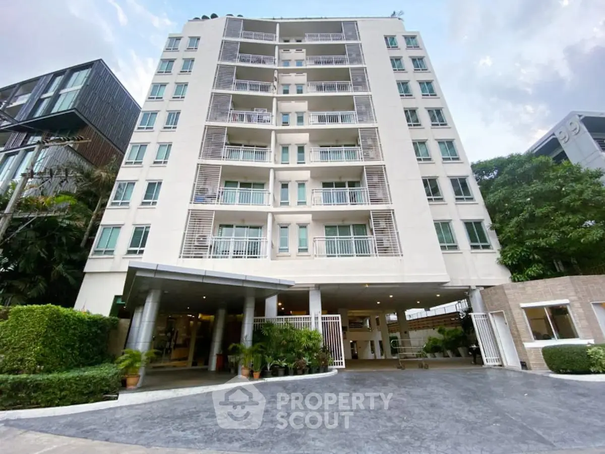 Modern multi-story residential building with lush greenery and spacious entrance.