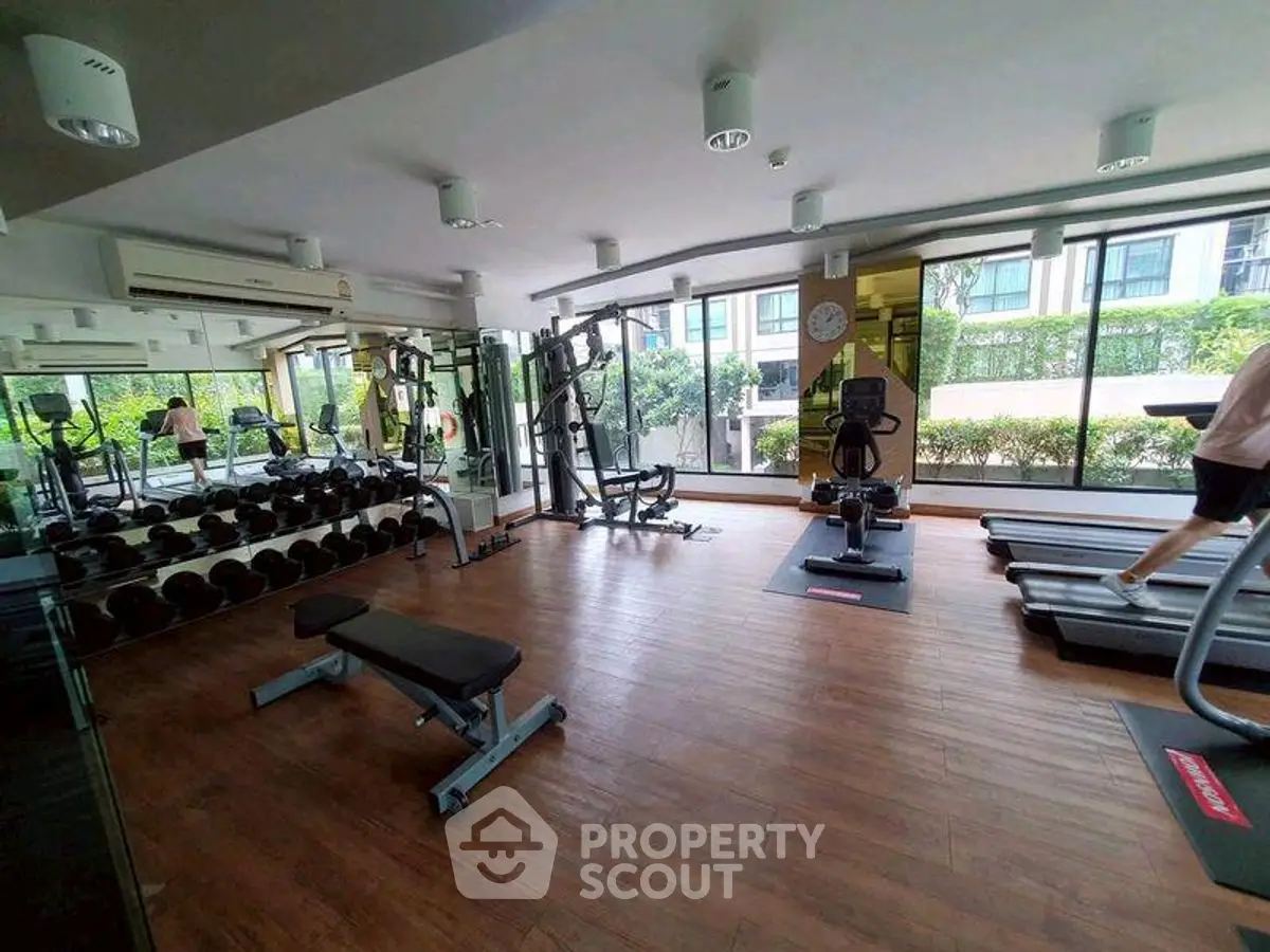 Modern gym with state-of-the-art equipment and large windows offering garden views.
