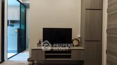 Modern living room with sleek TV stand and view into kitchen area