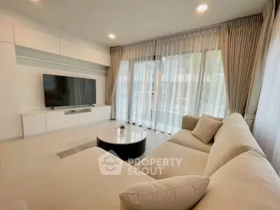 Spacious modern living room with large windows and elegant furnishings.