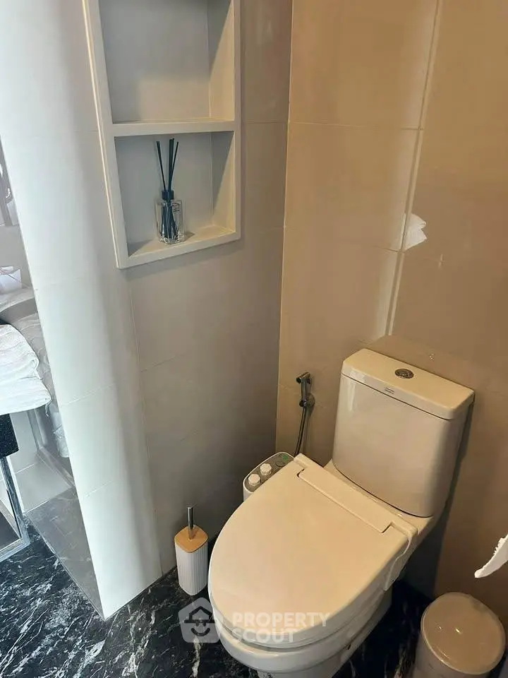Modern bathroom with sleek toilet and built-in shelving, featuring elegant marble flooring.