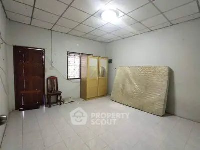 Spacious unfurnished room with tiled floor and ceiling light, featuring a wooden door and window.