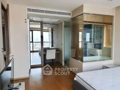 Modern bedroom with glass-enclosed bathroom and city view, featuring sleek wooden flooring and contemporary design.
