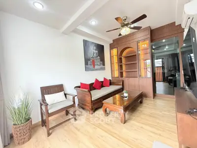 Charming living room with wooden furniture and ceiling fan, featuring elegant decor and cozy ambiance.