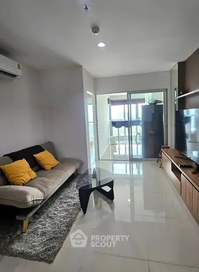 Modern living room with sleek furniture and large glass doors leading to a balcony.