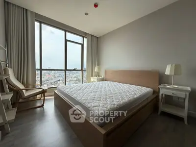 Spacious bedroom with city view, modern furniture, and large window for natural light.