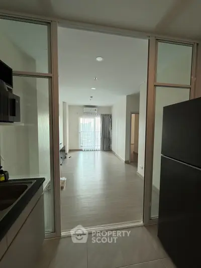 Modern open-layout kitchen leading to spacious living room with large windows