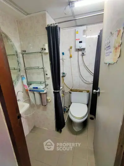 Compact bathroom with shower and water heater in cozy apartment