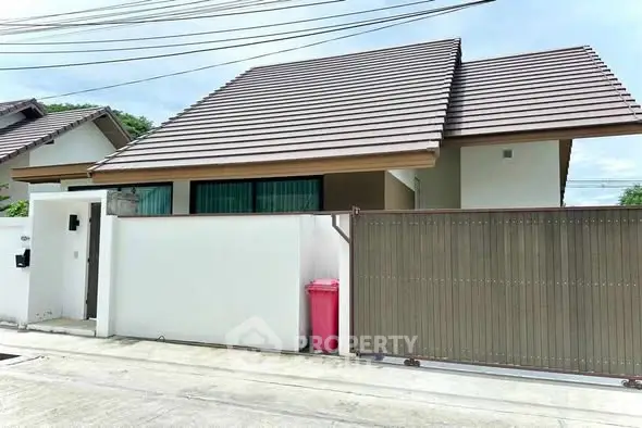 Charming single-story house with modern roof and gated entrance in a serene neighborhood.
