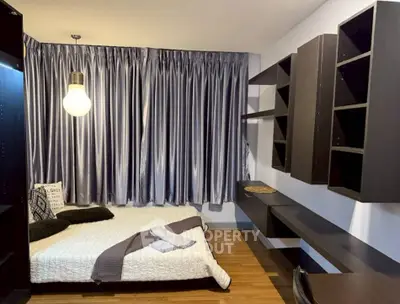 Modern bedroom with sleek shelving and cozy bed, featuring elegant curtains and warm lighting.