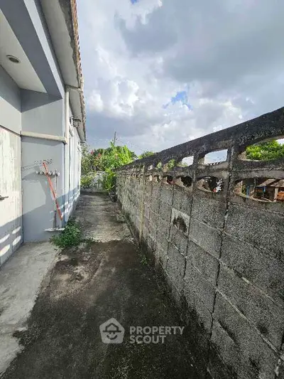 Spacious outdoor pathway with concrete wall and lush greenery