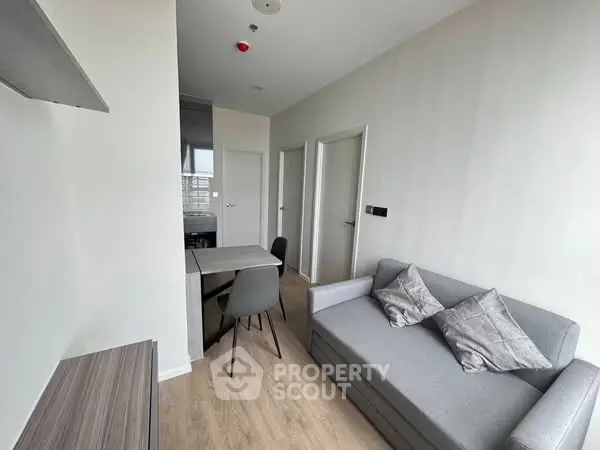 Modern living room with cozy gray sofa and dining area in a bright apartment.