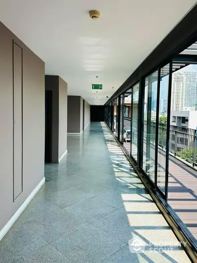 Spacious corridor with large windows offering city views in modern building.