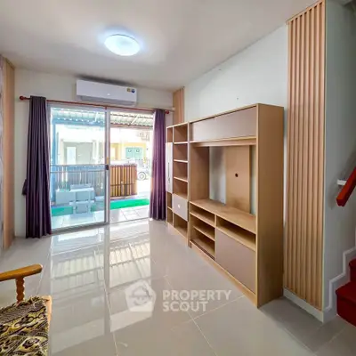 Spacious living room with modern shelving and large window opening to a balcony, perfect for natural light.