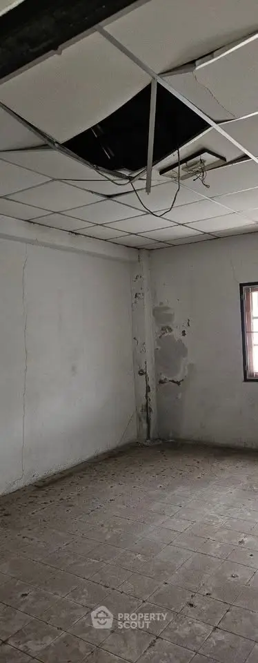 Spacious room with potential for renovation, featuring high ceilings and natural light from a window.