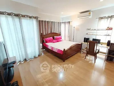 Spacious bedroom with elegant wooden bed and modern decor, featuring ample natural light and cozy ambiance.