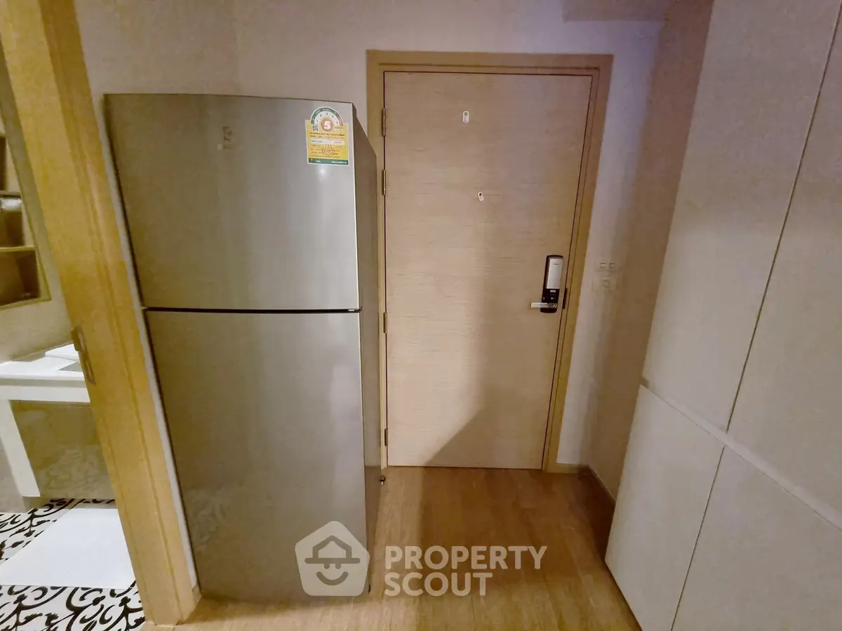 Modern apartment entryway with sleek fridge and stylish flooring