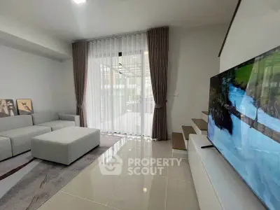Modern living room with sleek design, large TV, and natural light through floor-to-ceiling windows.