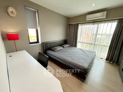 Modern bedroom with large window and stylish decor in a high-rise apartment.