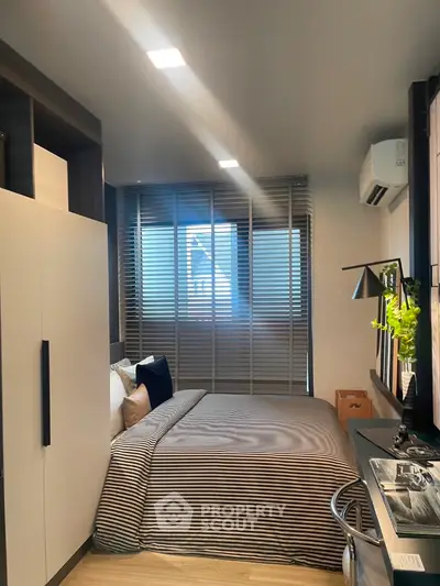 Modern bedroom with stylish decor and natural light, featuring a cozy bed and sleek furnishings.