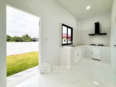 Bright modern kitchen with open layout and garden view, featuring sleek countertops and gas stove.