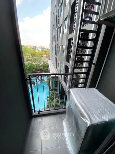Modern apartment balcony with pool view and cityscape, ideal for urban living.
