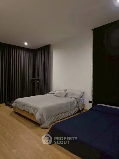 Spacious bedroom with modern decor and cozy ambiance, featuring two comfortable beds and elegant curtains.
