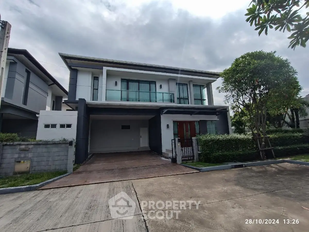 Modern two-story house with large windows and driveway in suburban neighborhood.