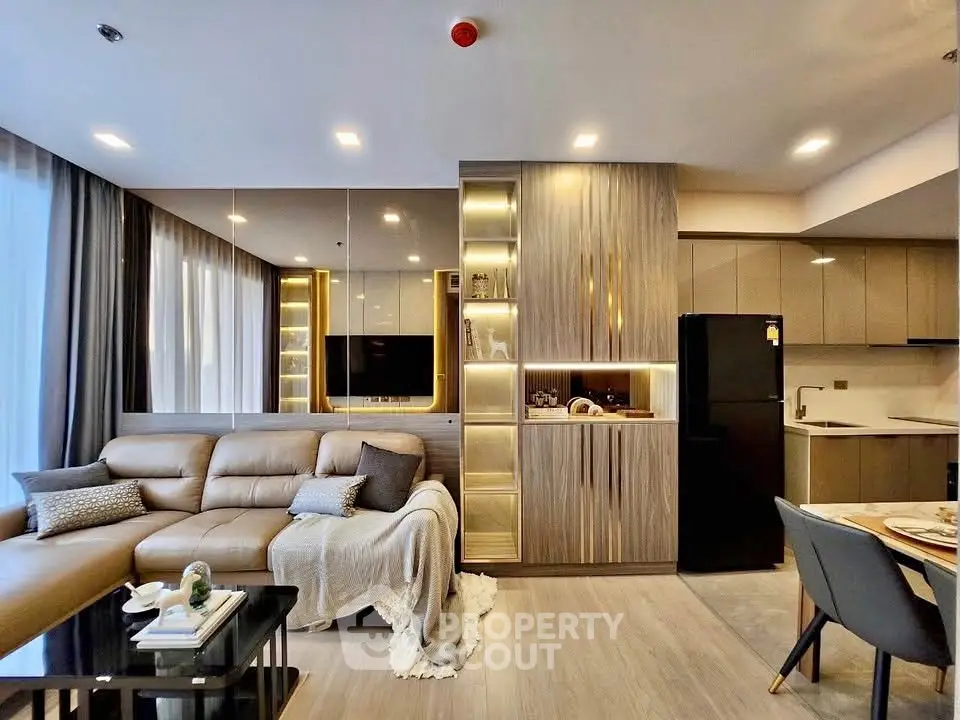 Modern open-layout living room with sleek kitchen, cozy sofa, and elegant lighting.