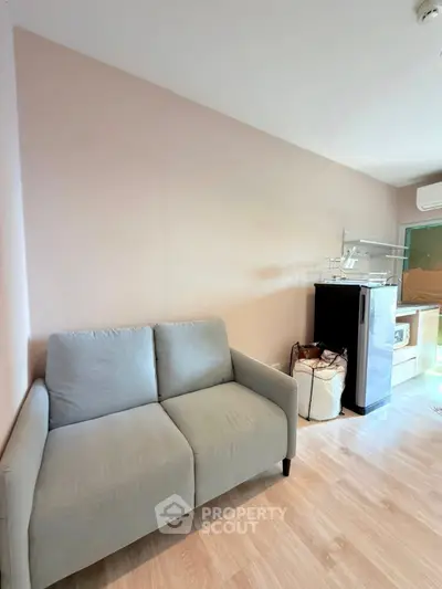 Cozy living room with modern kitchenette and compact appliances in a stylish apartment.