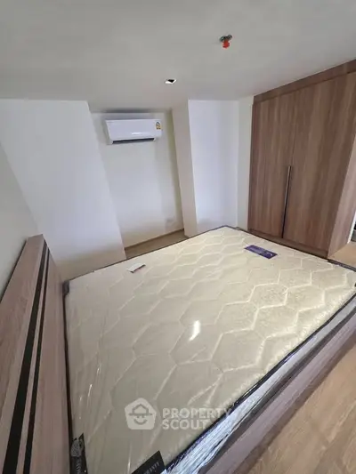Modern bedroom with new mattress, built-in wardrobe, and air conditioning unit.