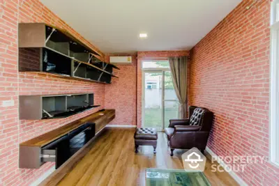 Stylish living room with brick walls and modern furniture, featuring a cozy leather armchair and open shelving.