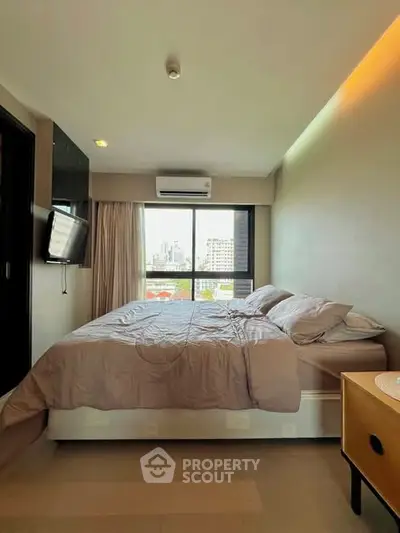 Cozy bedroom with city view, modern furnishings, and ample natural light.