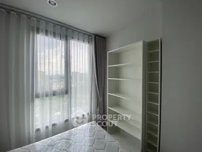 Bright bedroom with large window and white shelving unit.