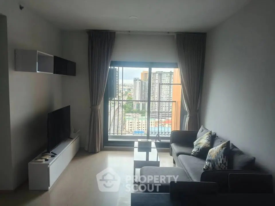Modern living room with city view, featuring sleek furniture and large windows for natural light.