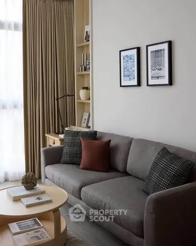 Stylish living room with modern gray sofa, elegant decor, and natural light from large window.