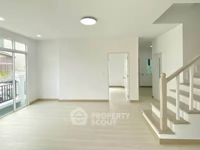 Spacious modern living room with natural light and elegant staircase in a contemporary home.